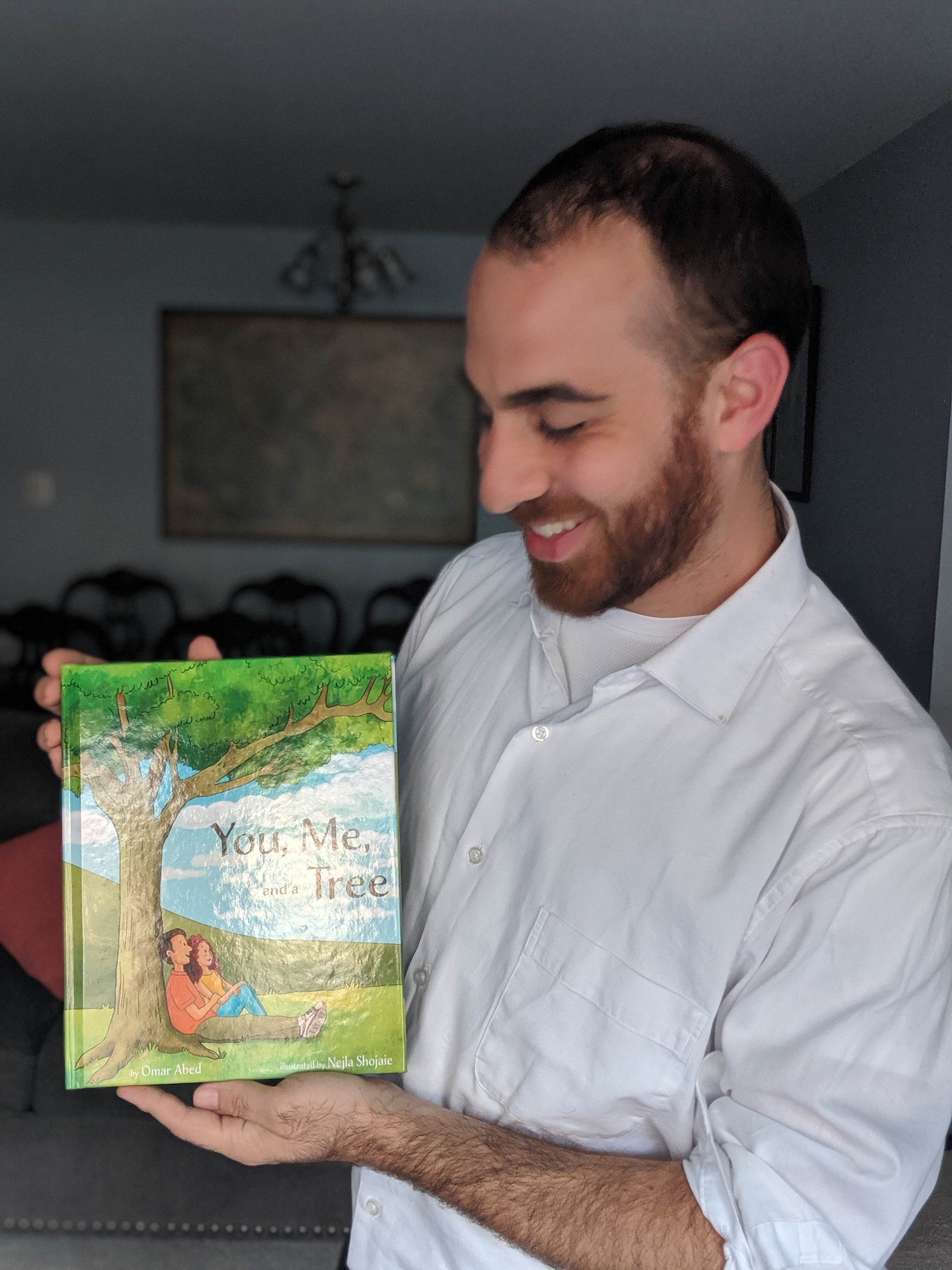 Omar holding a copy of You, Me, and a Tree
