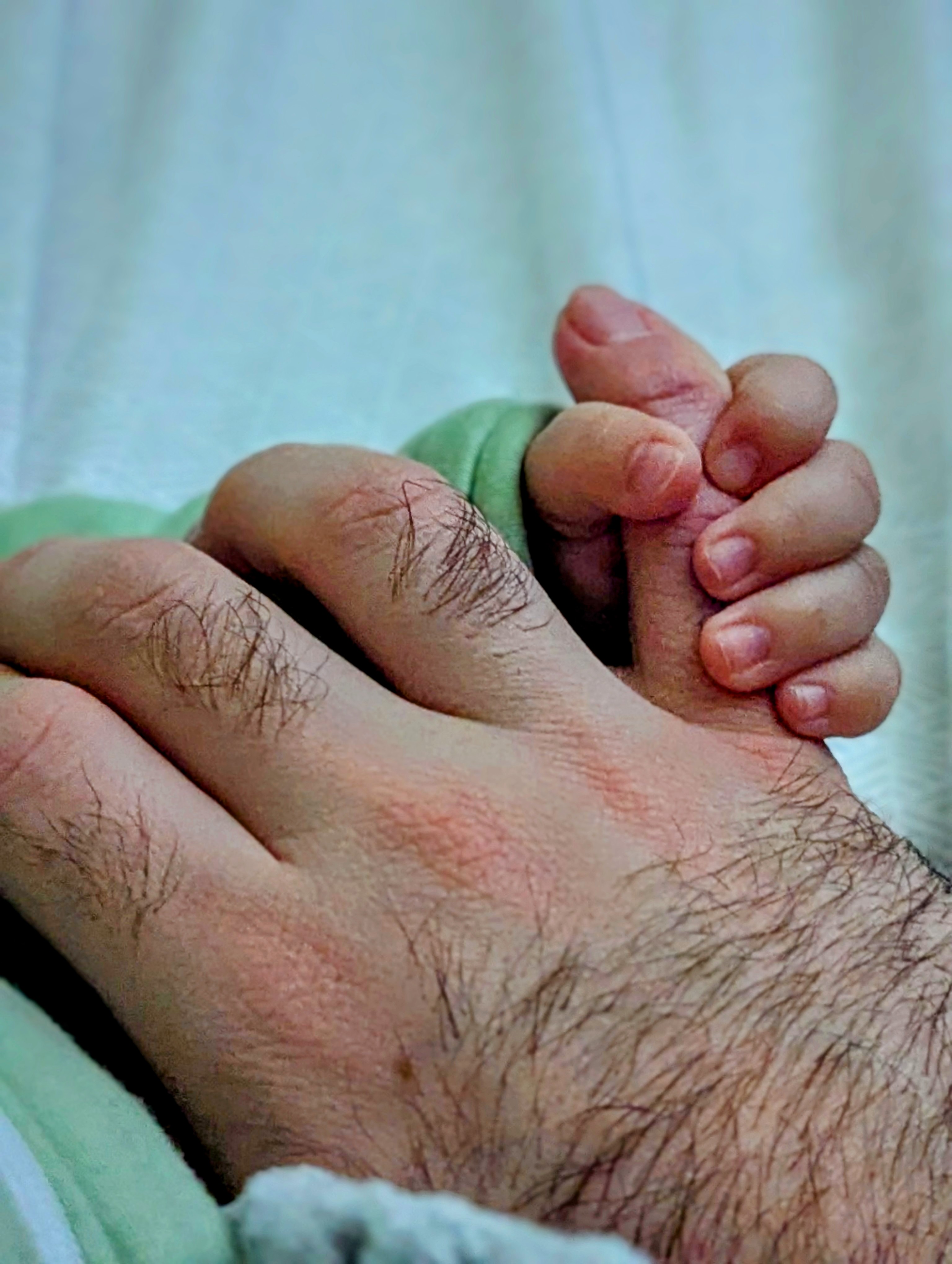 A baby grabbing onto Omar's pinky